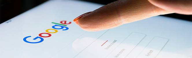 Un doigt appuyant sur la barre de recherche de Google.